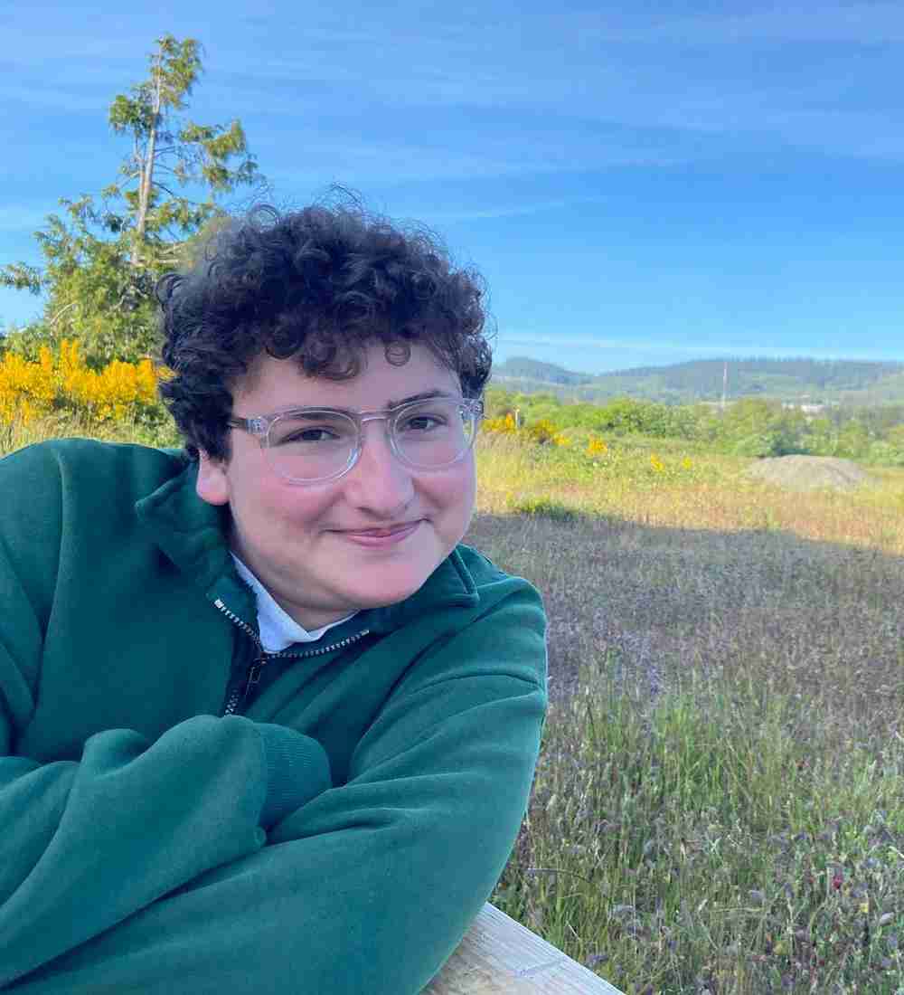 Smiling young man sitting in front of a field.