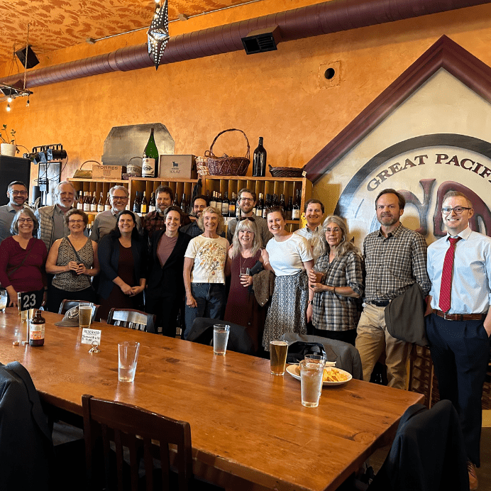 A row of people stand in a bar smiling at the camera.