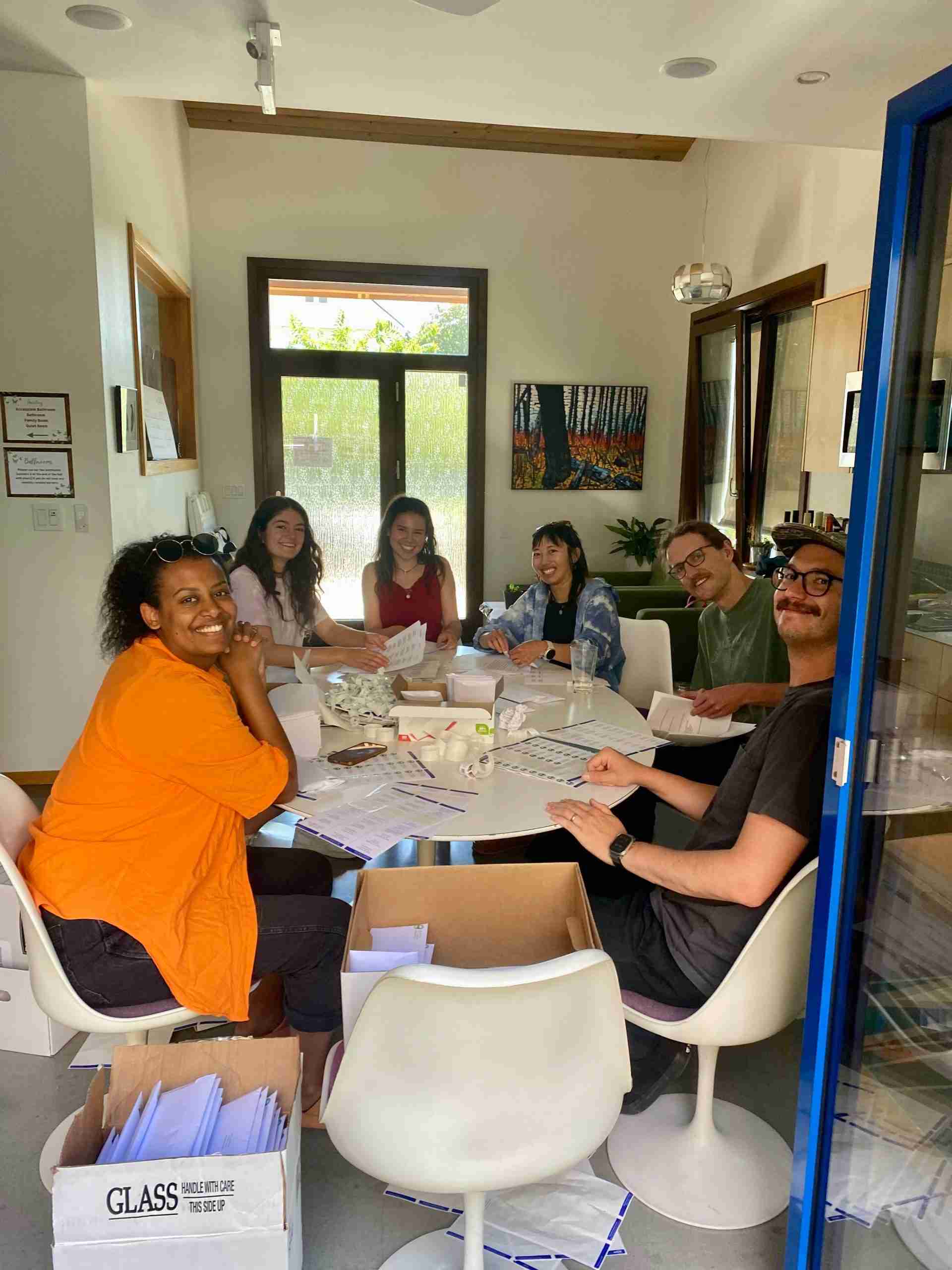 Staff sitting around a table covered in paper and envelopes