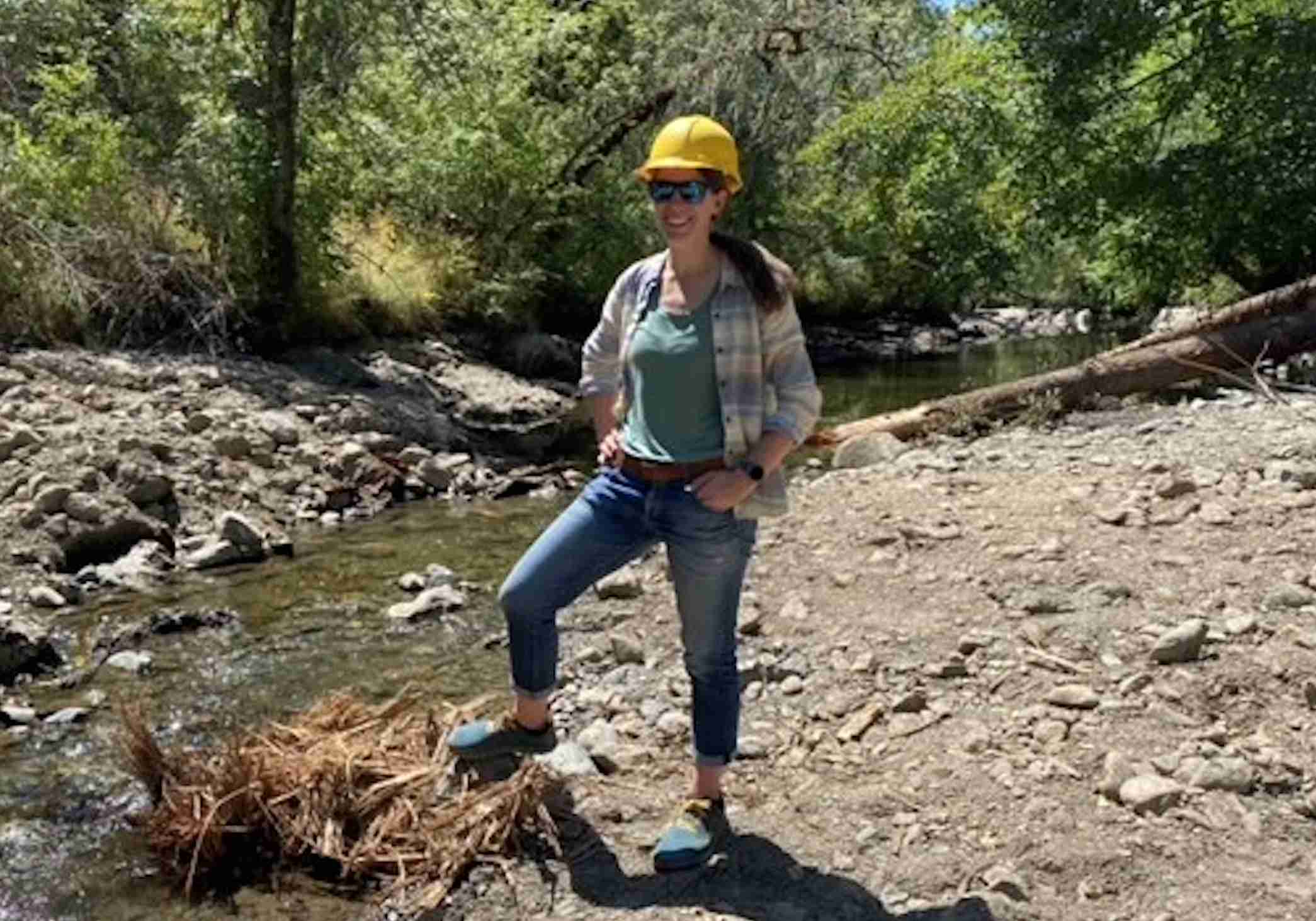 woman in front of a river smiling